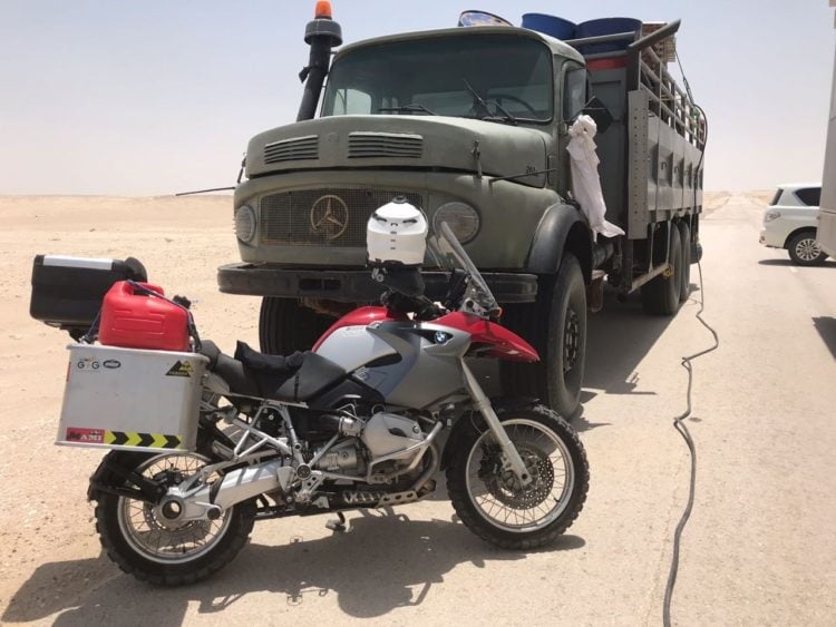 Mercedes truck carrying a massive generator and diesel tank, with cables stretching over to power the mobile home.
