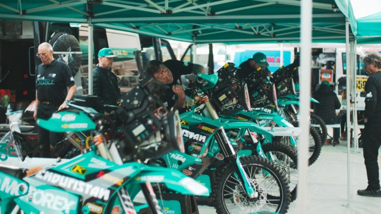 Africa Eco Race – Team Bivouac, mechanics working on bikes, riders in a different areas focussing on their tasks or resting.